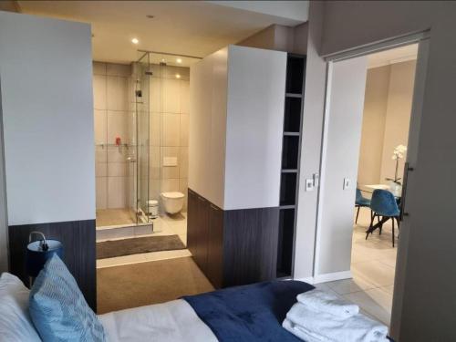 a bedroom with a bed and a bathroom with a shower at Menlyn Maine Apartments in Pretoria