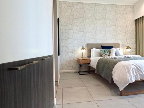 a bedroom with a bed and a table with a lamp at Menlyn Maine Apartments in Pretoria