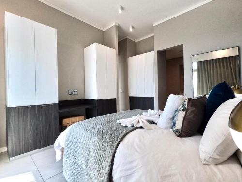 a bedroom with a large bed with white cabinets at Menlyn Maine Apartments in Pretoria