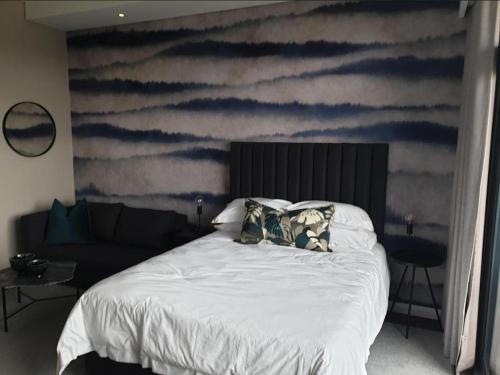 a bedroom with a bed with a painting of clouds at Menlyn Maine Apartments in Pretoria
