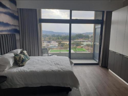 a bedroom with a bed and a large window at Menlyn Maine Apartments in Pretoria