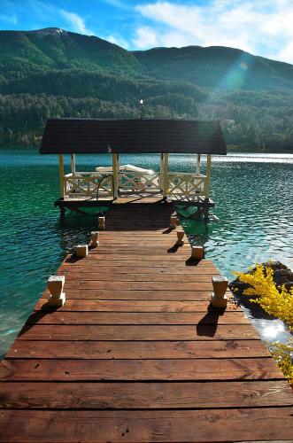 a bench sitting on a wooden bridge over a lake at Dos Bahias Lake Resort in Villa La Angostura