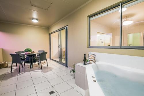 baño con bañera y mesa con sillas en 1770 Lagoons Central Apartment Resort Official, en Agnes Water