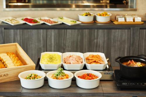 a buffet with bowls of different types of food at ICI HOTEL Tokyo Hatchobori in Tokyo