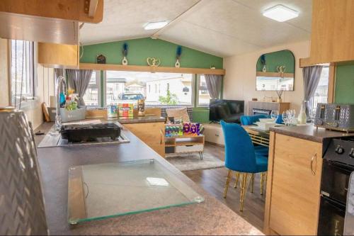 a kitchen with green walls and a counter with blue chairs at Tattershall Lakes Private Hot Tub Lodge - sleeps 6 in Lincoln