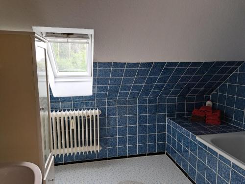 a blue tiled bathroom with a tub and a window at Gästehaus "Ruth" in Neugaude