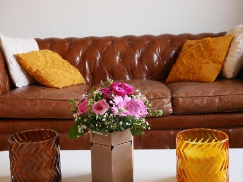 eine Vase mit Blumen auf einem Tisch vor einer Couch in der Unterkunft La loveroom de l'Artois in Souchez