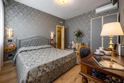 a bedroom with a bed and a desk and a table with a lamp at Hotel Apostoli Garden in Venice