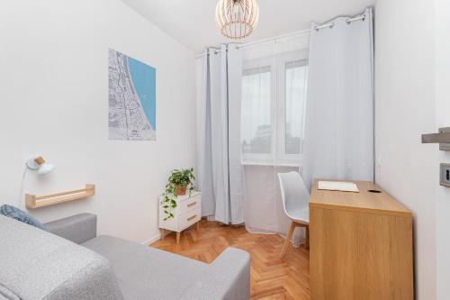 Kleines weißes Zimmer mit einem Schreibtisch und einem Bett. in der Unterkunft Cosy Apartment for 5 Guests Gdańsk Wrzeszcz by Renters in Danzig