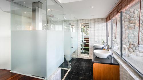 La salle de bains est pourvue de 2 lavabos et d'une douche en verre. dans l'établissement Villa Rom Trai, à Kathu