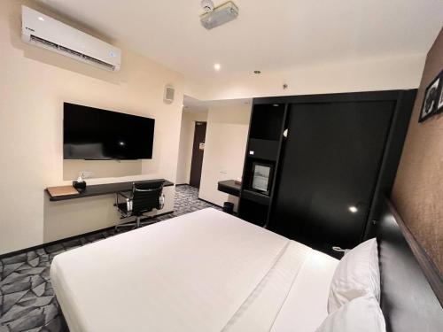 Hotel Aman Kuala Lumpur في كوالالمبور: غرفة فندقية بسرير وتلفزيون بشاشة مسطحة