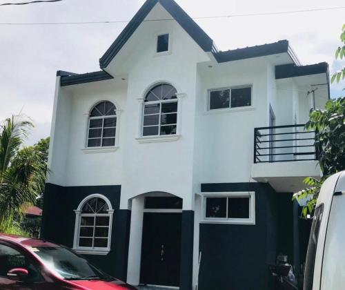 une maison blanche et noire avec des voitures garées devant elle dans l'établissement CCJ Villa, à Bacolod