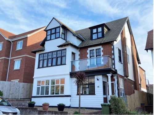 a white house with black windows at Bright, spacious flat close to beach, Cliff Road in Sheringham
