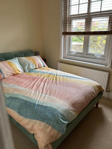 an unmade bed in a bedroom with a window at Bright, spacious flat close to beach, Cliff Road in Sheringham