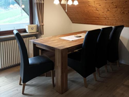 mesa de comedor con sillas negras y mesa de madera en Ferienwohnung Wiesenblick, en Oberharmersbach