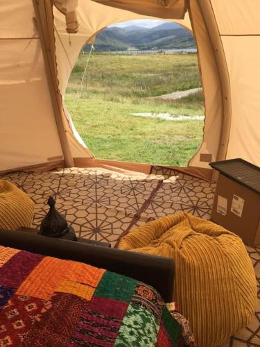 a tent with a bed and a view of a field at sterlochy dome in Lochcarron