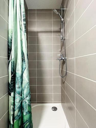 La salle de bains carrelée est pourvue d'une douche avec rideau de douche. dans l'établissement Zen et détente, à Roanne