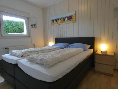 una camera con 2 letti con lenzuola bianche e cuscini blu di Schönes Ferienhaus in Husen mit Terrasse und Garten a Lichtenau