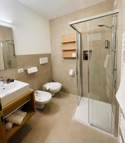 a bathroom with a shower and a toilet and a sink at Apparthotel Central in Campo Tures