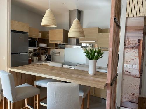 une cuisine avec un comptoir en bois et des chaises blanches dans l'établissement Arcachon, à Arcachon
