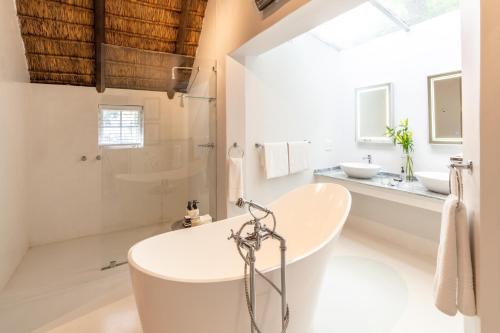 a white bathroom with a tub and two sinks at Hunter's Country House in Plettenberg Bay