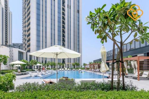 a swimming pool with an umbrella and chairs and buildings at Keysplease Spectacular Views Modern 1BR Creek Gate 602 in Dubai