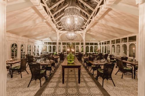 a dining room with tables and chairs and a chandelier at Hunter's Country House in Plettenberg Bay