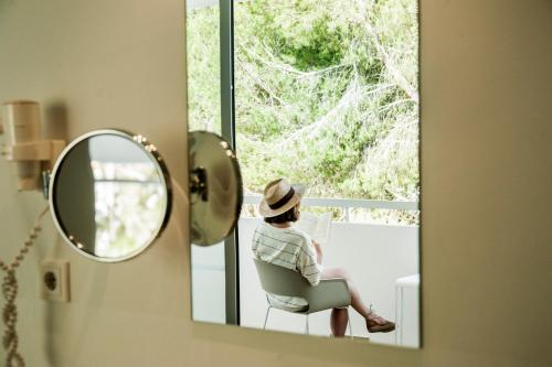 a woman sitting in a chair in front of a mirror at Hotel Anfora Ibiza in Es Cana