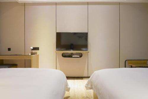 a hotel room with two beds and a flat screen tv at Paco Hotel Tiyuxilu Metro Guangzhou-Free Shuttle Bus during Canton Fair&5 Min walk to Canton Fair Buyer Registration Store in Guangzhou