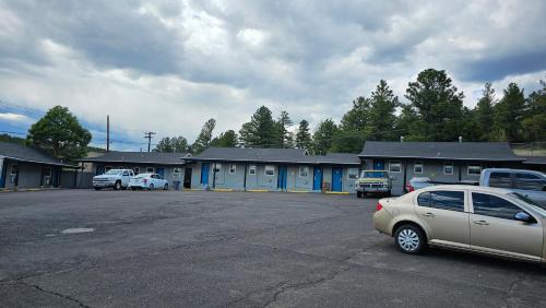 a parking lot with cars parked in front of a building at Travelers Inn in Flagstaff