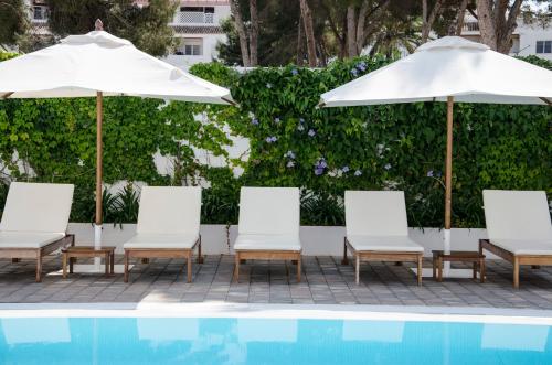 a group of chairs and umbrellas next to a pool at Hotel Anfora Ibiza in Es Cana