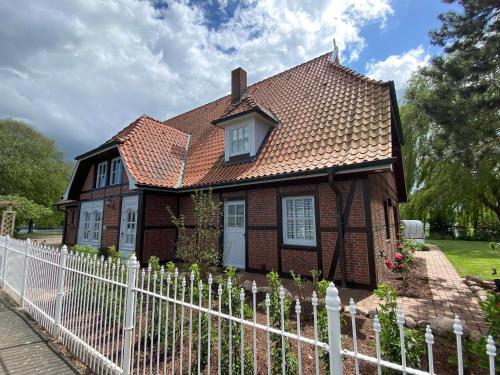 a small brown house with a white fence at Landhaus Lotten in Winsen Luhe