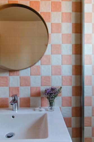 a bathroom sink with a mirror and a vase of flowers at Hotel Santo António de Fátima in Fátima