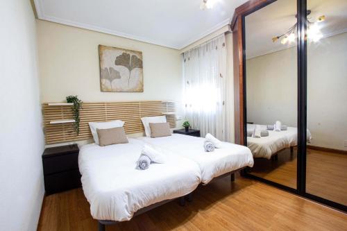 1 Schlafzimmer mit 2 Betten und einem großen Spiegel in der Unterkunft Acogedor piso de 6 camas in Salamanca