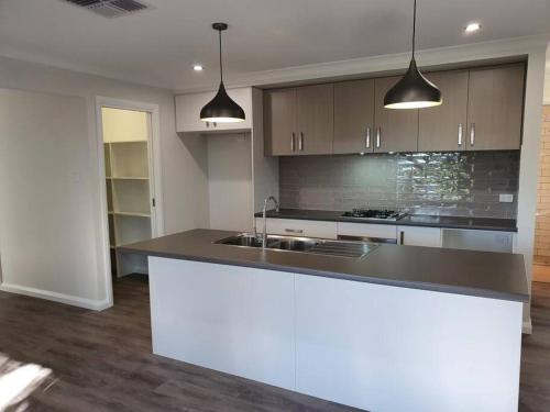 a kitchen with a black counter top and some lights at Killara Kottage in Tumut
