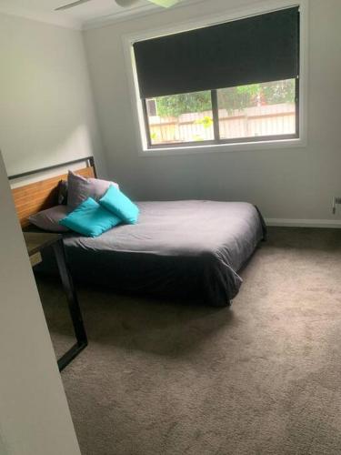 a bedroom with a bed with pillows and a window at Killara Kottage in Tumut