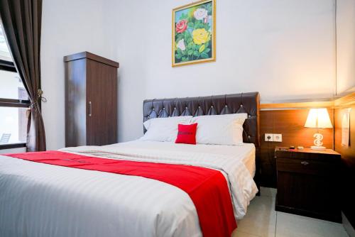 a bedroom with a large bed with a red blanket at RedDoorz Syariah near Unila in Bandar Lampung