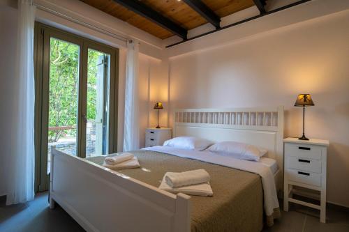 a white bedroom with a bed and a window at Villa Jasmine in Platanidia