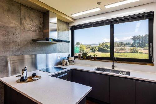 a kitchen with a sink and a large window at Nobhillstay Jeju in Jeju