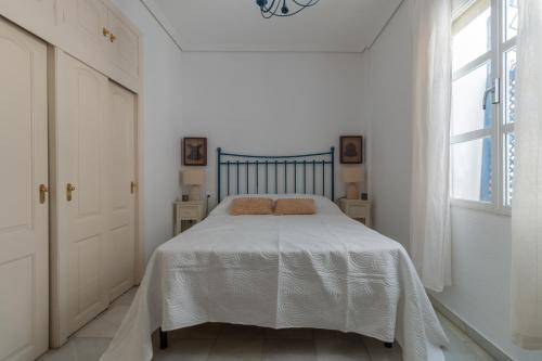 a white bedroom with a bed with a white blanket at Apartamento Azonaicas in Córdoba