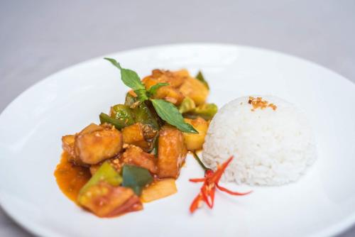 a plate of food with rice on a white plate at Pomelo Outpost Cambodia ដំណាក់ភ្នំក្រោម in Phumĭ Rœssei Lŭk