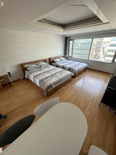 a room with two beds and a table in it at Hongdae Guesthouse 1min from Hongik Uni station Exit #1 in Seoul