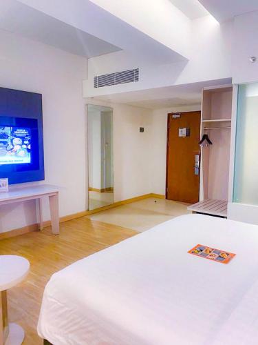 a room with a bed and a tv on a wall at Harper Palembang by ASTON in Palembang