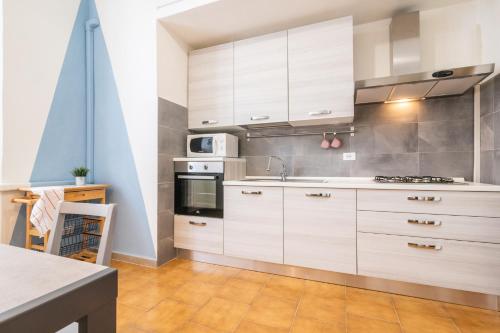 a kitchen with white cabinets and a stove top oven at Travel & Station Apartament in Livorno