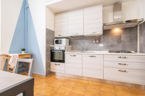 a kitchen with white cabinets and a stove top oven at Travel Station Apartment by Pleiades Home in Livorno