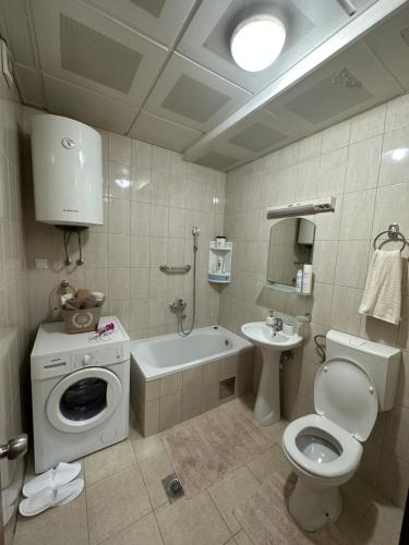 a bathroom with a toilet a sink and a washing machine at Bella Apartman in Podgorica