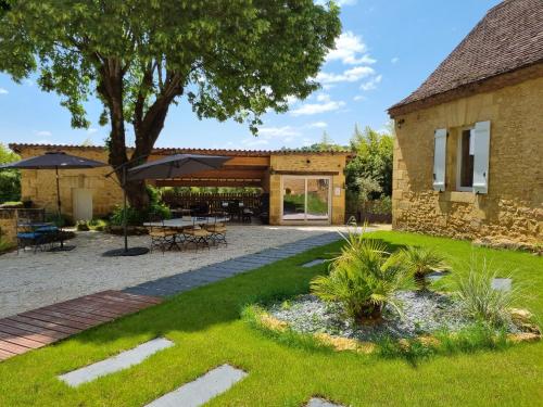 a garden with a patio and a building at Le Clos de la Canéda in Sarlat-la-Canéda