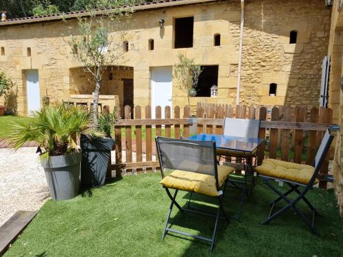 a patio with a table and chairs on the grass at Le Clos de la Canéda in Sarlat-la-Canéda