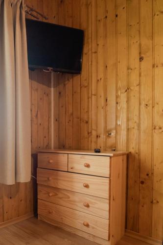 a bedroom with a dresser with a television on a wall at Biotour Camping & Restaurant in Ghimeş