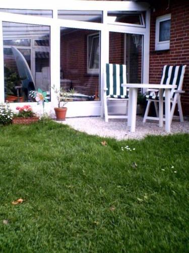 een patio met 2 stoelen en een tafel in het gras bij Haus-Halliger-Appartment-Ilse in Westerland